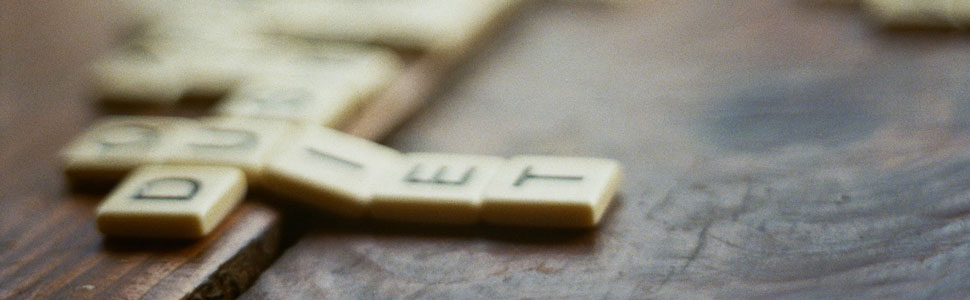 Closeup of lettered tiles from a Scrabble game on a wood surface.