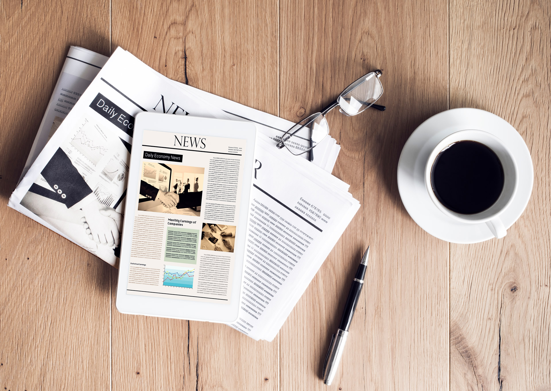 Newspaper with tablet and a cup of coffee on a wooden surface