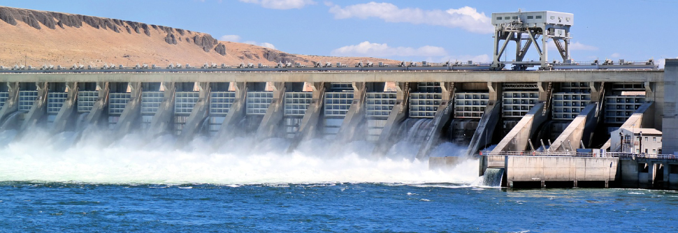 A large dam with water flowing into a large body of water