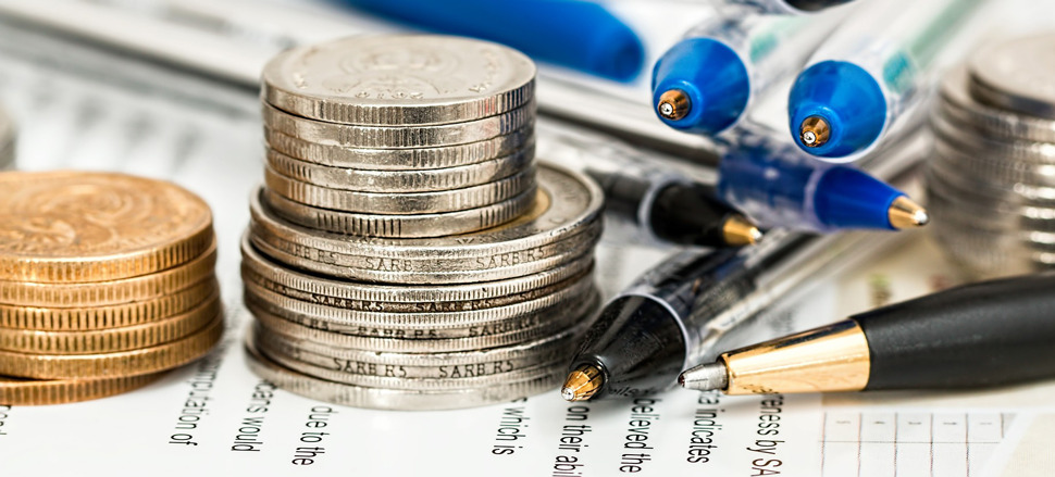 Closeup photo of coins and pens sitting on a sheet of paper.